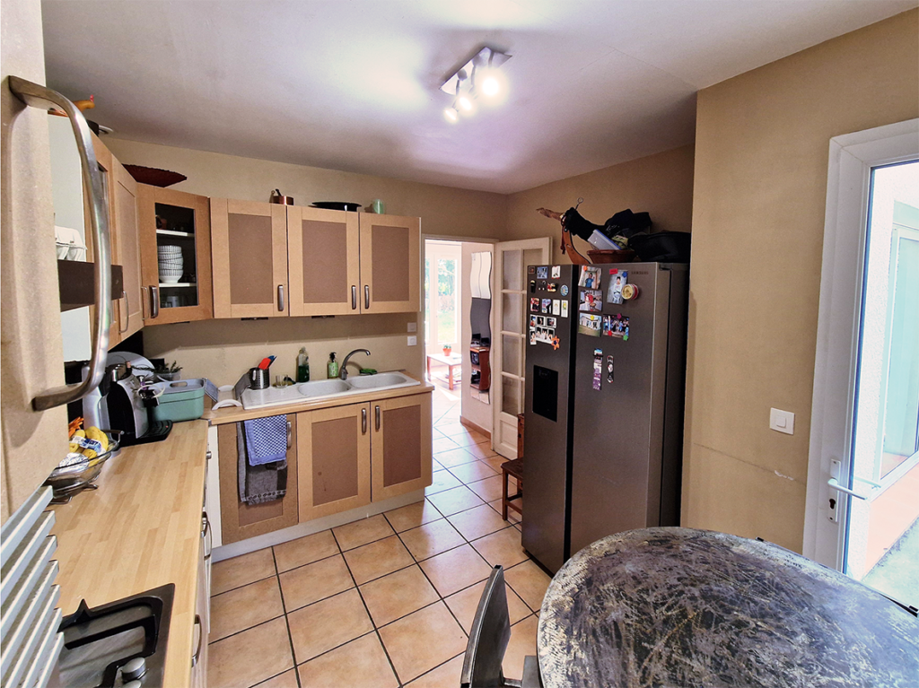 cuisine petite avec grand frigo américain au fond on devine une porte qui donne sur couloir et salon